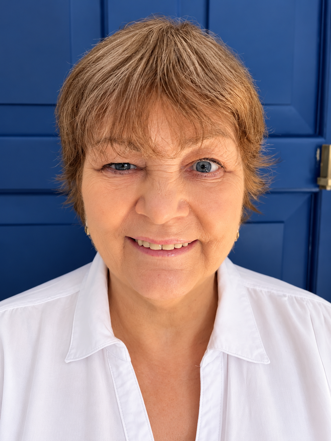 Helen Mc Crarren smiling in a white shirt in front of a blue door
